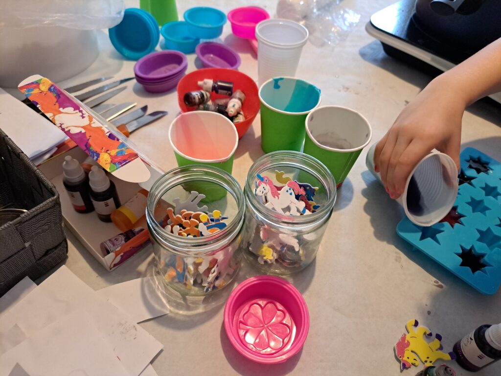 Kinder basteln an einem Tisch und gestalten bunte Kerzen